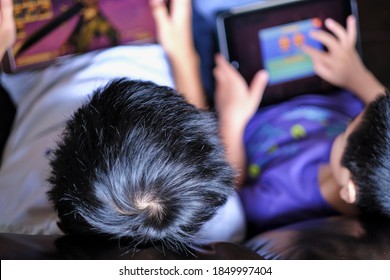 Top View Of Boy Brothers Sitting And Playing Online Games On Tablet Pads. Kids Spending More Time On Playing Video Games Under Covid-19 Pandemic Lockdown.