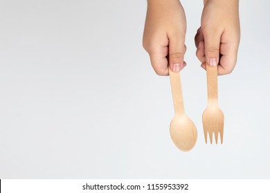 Top View Of Boy Hand Hold The Kitchenware Spoon And Fork Made From Leaf Sheath Of Palm Tree On White Isolated Background
