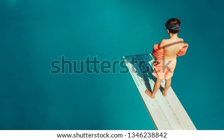 Top view of boy standing on spring board learning to dive during swimming class on a summer day. Boy learning swimming at outdoor pool. Stockfoto © 