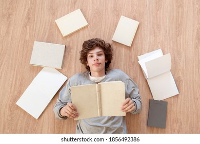 Top View Of A Boy Teenager Laying On The Floor And Reading Books, Learn And Study