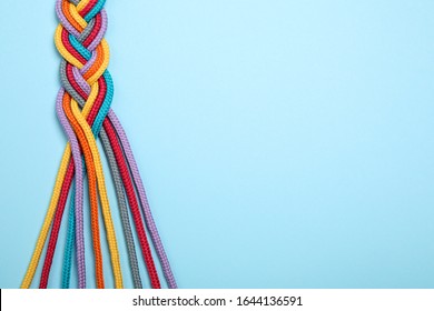 Top View Of Braided Colorful Ropes On Light Blue Background, Space For Text. Unity Concept