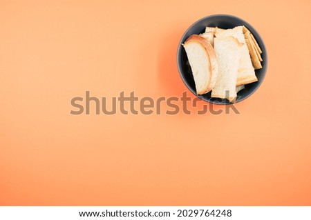 A top view of bread slices on a bowl isolated on an orangebackground