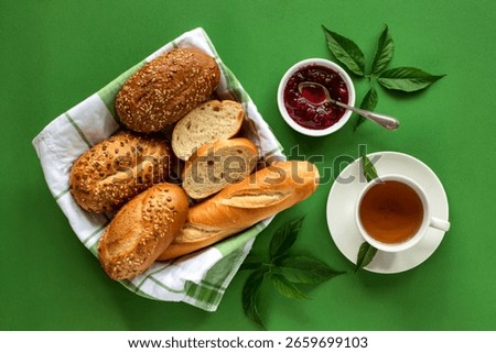 top view of breads as seeded brown cob and baguette slices in basket and raspberry jam