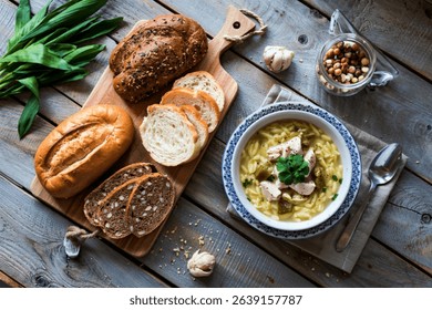 top view of breads as sliced rye and white ones on cutting board and bowl of chicken orzo soup