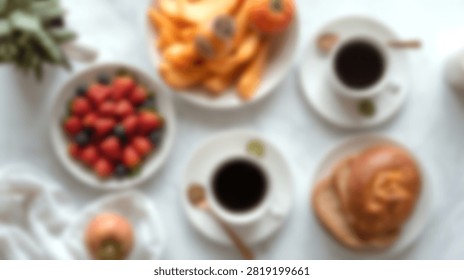 Top view of breakfast spread featuring black coffee fresh strawberries blueberries and sweet pastries on a white table