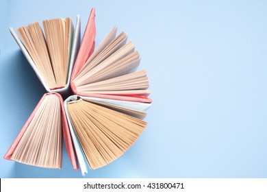 Top view of bright colorful hardback books in a circle. Open book, fanned pages.   Education essential for self improvement, gaining knowledge and success in our careers, business and personal lives.