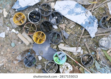 Top view of broken plastic caps and scattered debris on a dirty ground.
