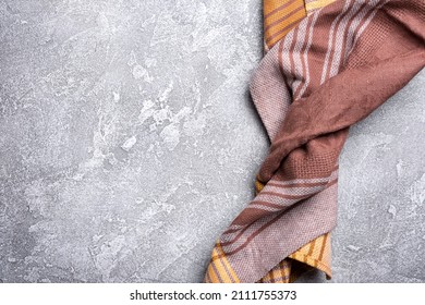 Top view of brown folded kitchen towel or serviette on grey concrete background