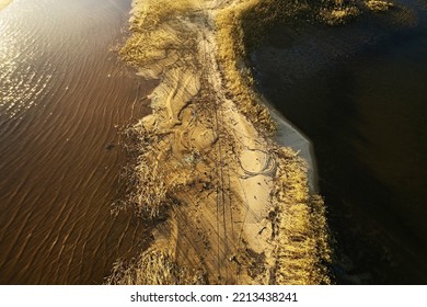 Top View Of The Brown Lake And Sandy Beach Overgrown With Dry Grass On A Bright Sunny Day. Aerial Photography Landscape In The Fall, Abstract Forms