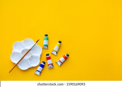 top view of brushes, color tubes and palette on yellow background, copy space, flat lay, paintings art concept - Powered by Shutterstock