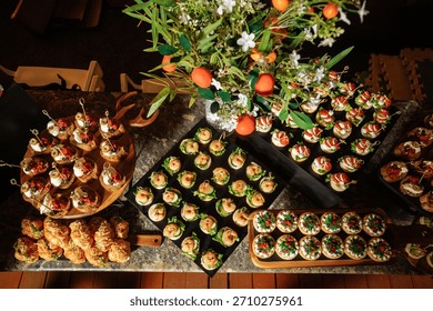 Top view of buffet table with canapes, flowers and oranges - luxurious catering setup.