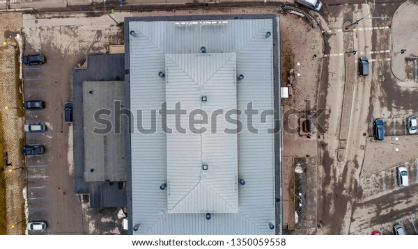 The top view of a building in Tartu Estonia the view\
of the big gray roof of the building with lots of cars parked on\
the side of it