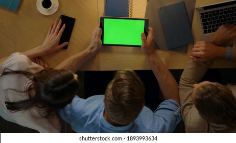 Top View Business Man With Green Screen Tablet Sitting At Table With Colleagues In Office. Young Entrepreneurs Analyzing Project Work Indoors. Creative Team Looking At Chroma Key Screen On Tablet