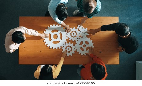 Top view of business people gathering white gear together at meeting table. Group start up team in casual cloth working together connecting cog together. Cooperate, teamwork,togetherness. Convocation. - Powered by Shutterstock