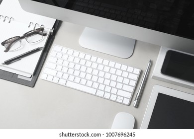 Top view of business workplace with computer, keyboard, white tablet, smartphone, pen, glasses