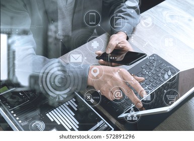 top view businessman hand using smart phone,mobile payments online shopping,omni channel,digital tablet docking keyboard computer,documents,in modern office wooden desk,virtual interface icon screen - Powered by Shutterstock