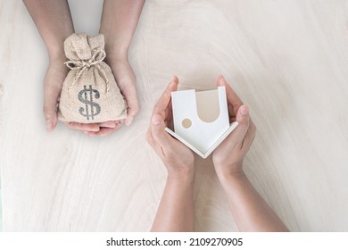 Top View Businessman And Investor Hand Hold Money Bag And The Home Model Presenting To Each Other In The Office, Saving Money For Buy House Or Loan For Plan Business Investment Of Real Estate Concept.