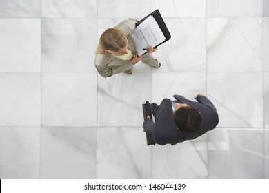 Top View Of A Businessman And Woman Conversing In Office Lobby