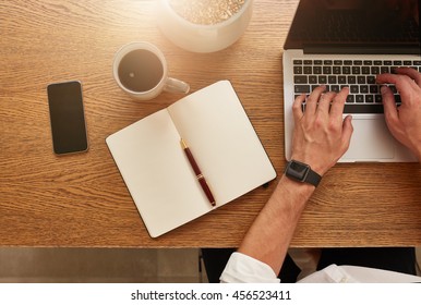 Top view of businessman working at his desk. Modern workplace with laptop, smartphone, diary and coffee cup. - Powered by Shutterstock