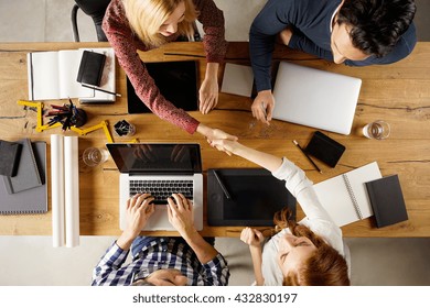 Top View Of Businesspeople Shaking Hands After Sealing A Deal. High Angle View Of Casual Businesswomen Shaking Hands After Concluding Business Agreement.