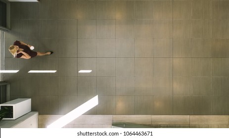 Top View Of A Businesswoman Entering Office Hallway With Coffee And Talking On Mobile Phone. Top View Of Businesswoman In Office Building Lobby.