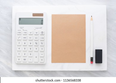 Top view of calculator, pencil, eraser and brown  notepad on white marble block and stack on grey marble table.Flat lay Mock up template for adding or display text or design.Stationery item - Shutterstock ID 1136568338