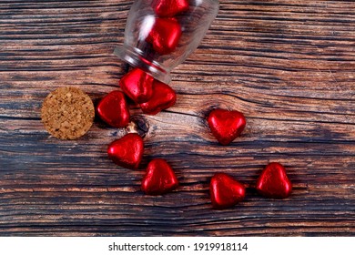 A top view of candy hearts pouring out of a jar