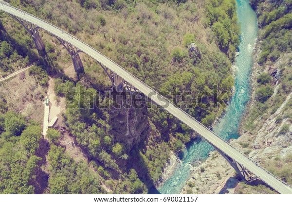 Top view of a car bridge across a river in the\
mountains. Toned