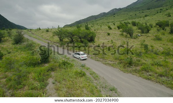 Top view of car traveling in mountain valley.\
Action. Traveling by car on mountain roads. Car goes along\
serpentine on background of green\
mountains