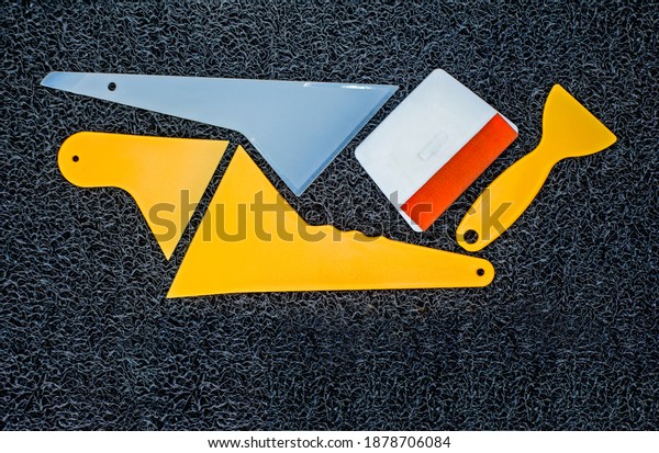 Top view of car\
window tint scraper squeegee wrapping vinyl film cleaning tool kits\
on black background.