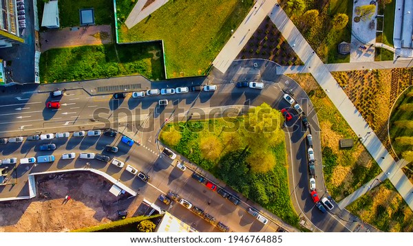 Top view of cars driving in Milan in the evening. Car\
traffic in the city area city live. The drone flies from top to\
bottom, shooting at parked cars right along the street. Milan,\
Italy, April 2021: 