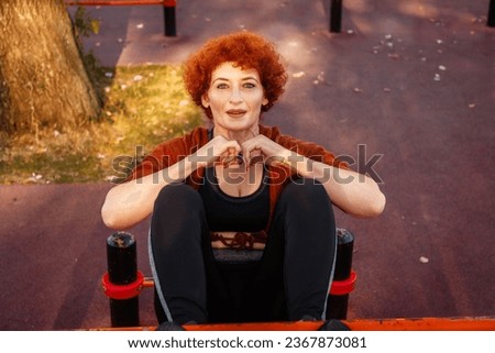 Top view of Caucasian adult woman does abdominal crunches training in city park. Concept of fitness and sport.