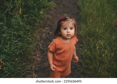 Top View Of A Caucasian Baby Girl With Brown Eyes Looking Up Thoughtfully. Girl Looking Up. Summer Nature. Beautiful Young Girl.