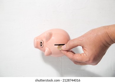 Top View Of A Caucasian Hand Putting A Coin In A Pinky Piggy Bank