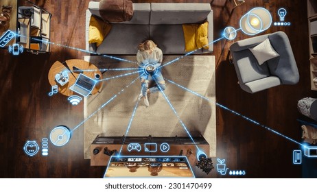 Top View Of Caucasian Woman In the Loft Apartment Sitting On Carpet Next To Couch and Connecting Smartphone to Smart Home System. VFX Edit Visualizing Connected Devices. Laptop, TV, Speaker. - Shutterstock ID 2301470499