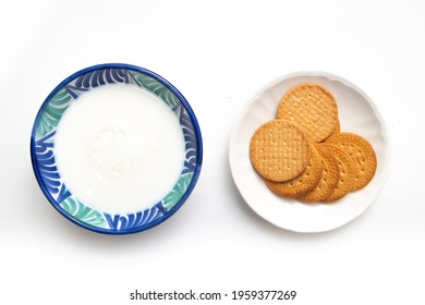 Top View Of A Ceramic Bowl With Milk And A Plate With Cookies On A White Background