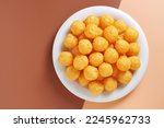 Top view of cheese puff balls in plate isolated on two-color background. Copy space