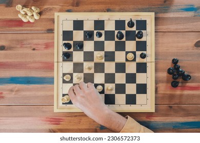 Top view of the chess board in full play, hand of a man in the game - Powered by Shutterstock