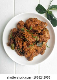 Top View Of Chicken Rendang On White Plate With White Wooden Background. Chicken Rendang Is A Famous Dish In Malaysia, Indonesia And Singapore. It Is Thick Chicken Stew With Spices And Coconut Milk. 