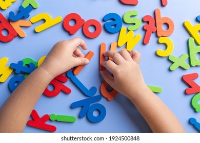 Top View Of Child Arm Learning Alphabet With Wooden Toys