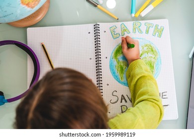 Top View Of Child Girl Draws Planet Earth With Wax Colors On School Notebook For Earth Day - Little Activist Girl Writes The Message Save The Planet - Protection Of Environment, Global Warming