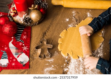 Top view, child hands preparing dough with small rolling pin for Christmas cookies, on a table with Christmas red decorations - Powered by Shutterstock