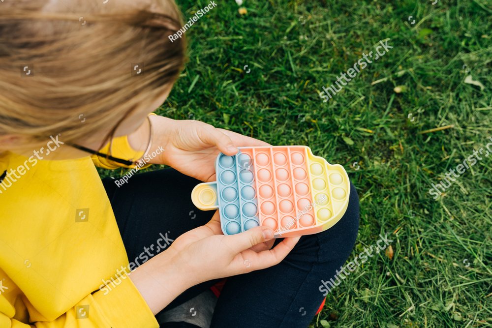 Top view of child playing with colorful poppit sensory game together ...