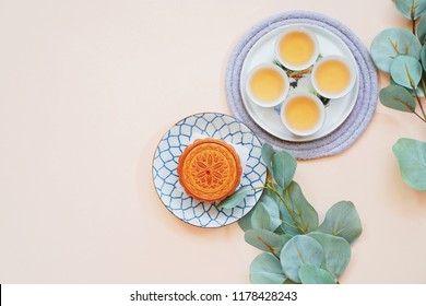 Top View Of Chinese Moon Cake With Hot Tea And Green Plant On Yellow Background, Holiday And Festival Concept