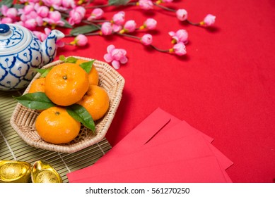 Top view chinese new year accessories Chinese new year festival Orange gold, leaf, wood basket, red packet, Sakura, teapot on red background.