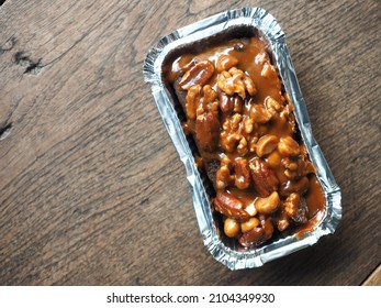 Top View Chocolate Butter Cake With Caramel Toffee Nut Topping In Baking Tin Foil On Wooden Board