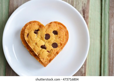 Top view of chocolate chip cookies in the shape of heart on white plate, with wooden background. (Concept about love and relationship) - Powered by Shutterstock