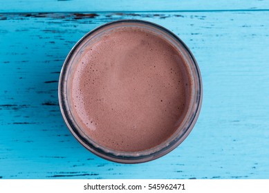 Top view of chocolate milkshake on blue wooden table