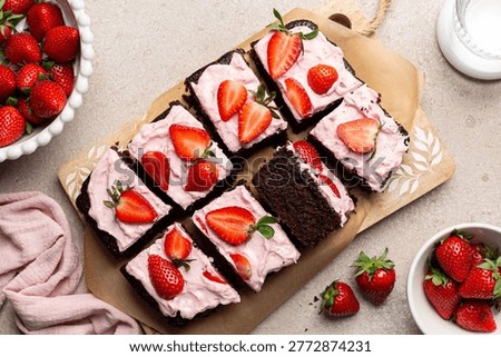 Top view of Chocolate Sheet Cake with Strawberry and cream cheese  frosting and fresh strawberries. Homemade pastry. Sliced dessert. Beige table. 