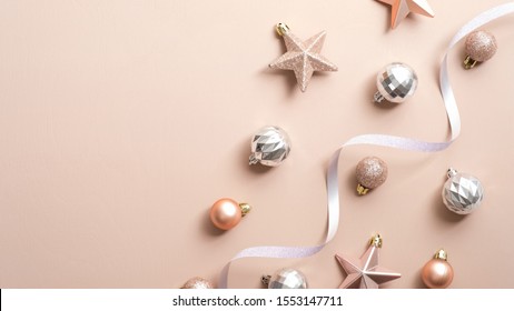 Top View Christmas Balls, Stars And Ribbon On Copper Or Champagne Pink Background. Flat Lay Glamour Stylish Fashion Decorations. Elegant Christmas Party Banner Mockup